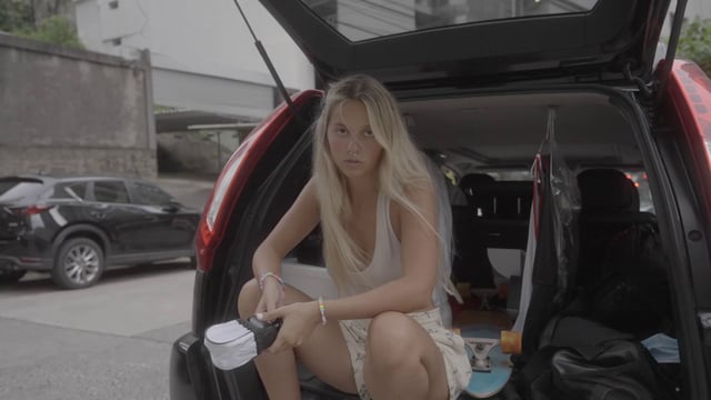 A blonde girl sitting in the trunk of a car