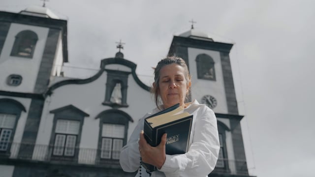 A religious woman reads a Bible near a church