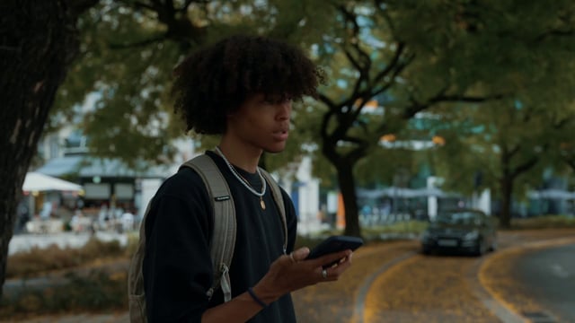 Un chico habla por un teléfono inteligente en una calle.