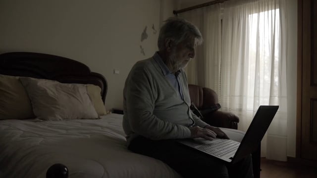 Un anciano concentrado que usa una computadora portátil