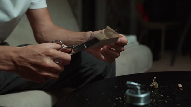 Un hombre corta un papel de fumar