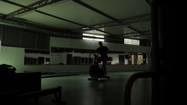Un atleta fuerte está entrenando en la bicicleta estática