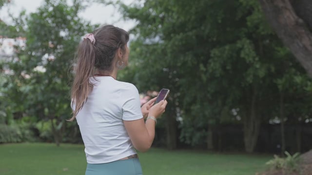 一名女子在公园里为一棵大树拍照