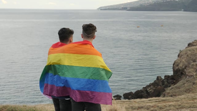Pareja gay envuelta en una bandera del orgullo