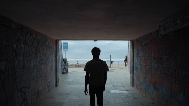 A man walking through a tunnel to the beach
