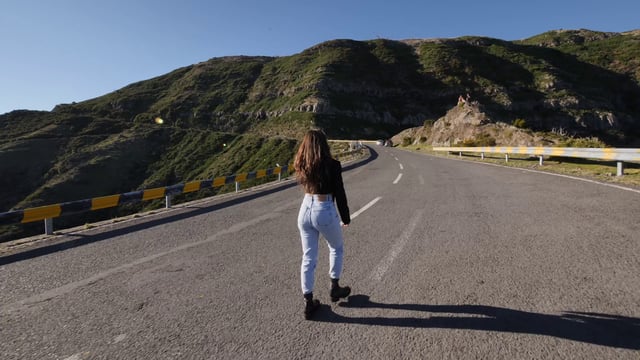 Una niña caminando por el camino de la montaña