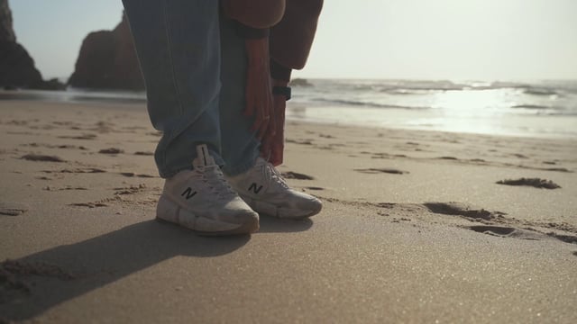 Zapatillas en las piernas del hombre en la playa