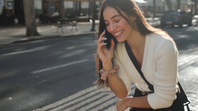 Chica habla por teléfono inteligente mientras camina por la calle