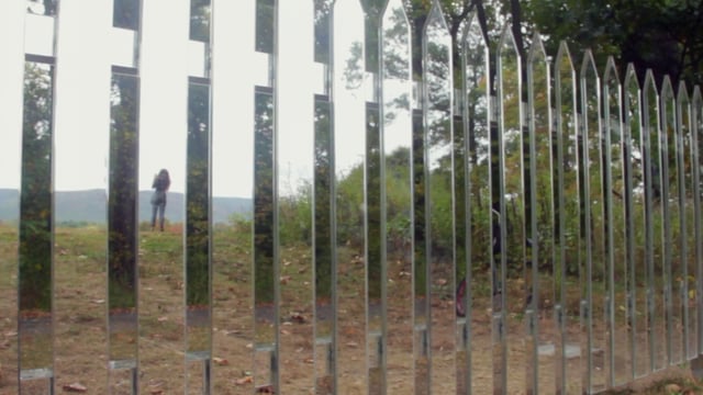 People in the reflection of a fence