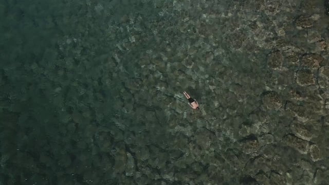 A man diving into crystal clear water and swimming