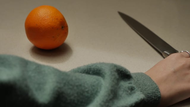 Woman cutting an orange with a sharp knife