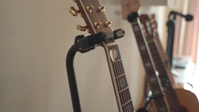 A hand taking a guitar from its stand