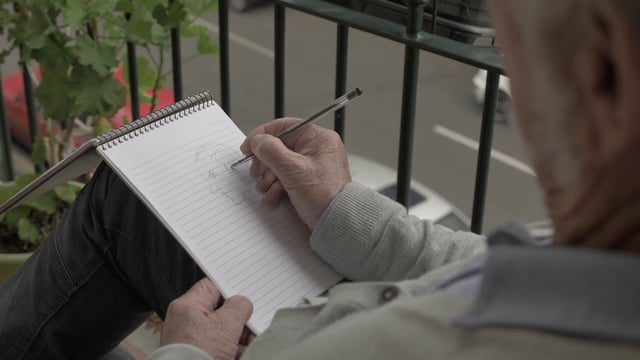 Vista superior de un anciano pintando un retrato en su cuaderno