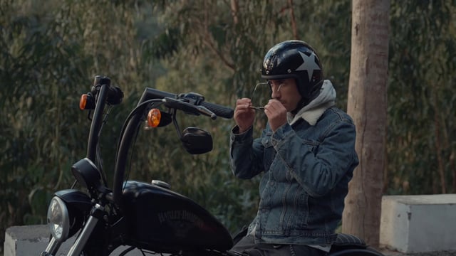 A motorcyclist putting on glasses and accelerating his bike 