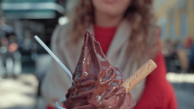 Una niña prueba un helado de chocolate en un café de la calle