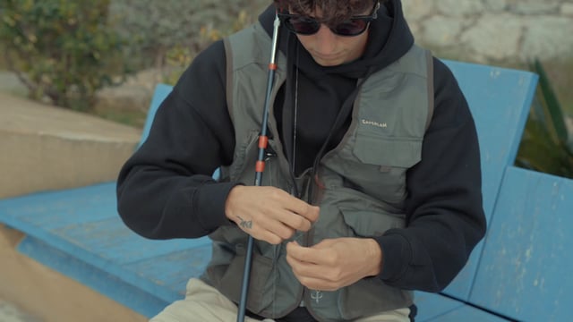 A fisherman attaches a hook to a fishing line