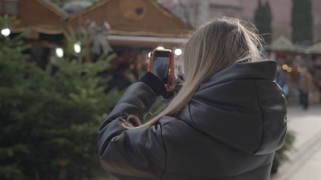 Una niña está grabando el video de los árboles de Navidad y la feria.