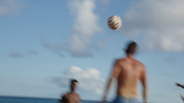Chicos jugando al fútbol en la playa