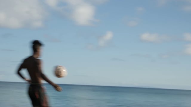 Chicos jugando al fútbol en la playa.