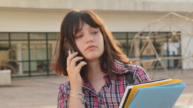 Estudiante hablando por teléfono en el campus de la escuela