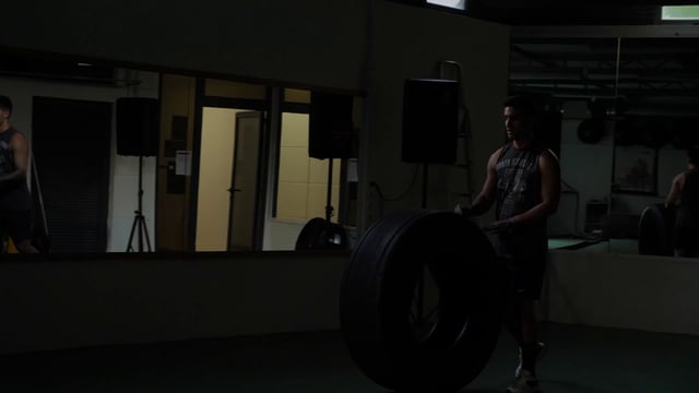 Atleta rueda el neumático en el gimnasio