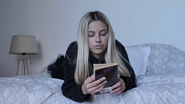 Girl reading a book in bed 