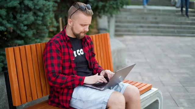 Freelancer working outdoors on laptop