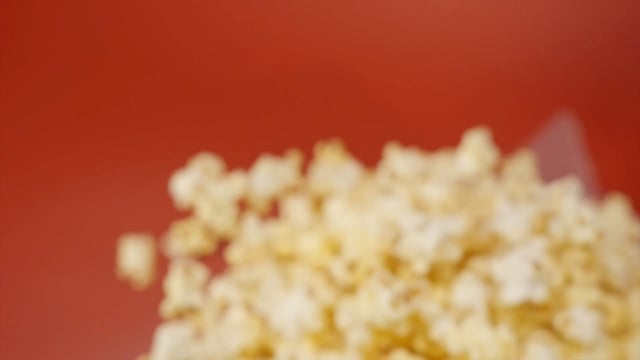 Extreme close-up of popcorn flying against a red background