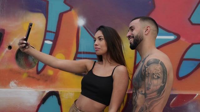 Couple takes a selfie in front of graffiti
