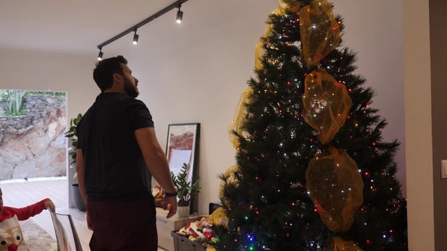 Man adjusts Christmas tree decorations