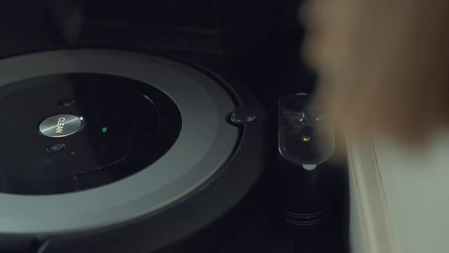 Pressing the ‘clean’ button on a robot vacuum cleaner