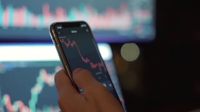 A trader performing financial analysis of cryptocurrency using a phone app
