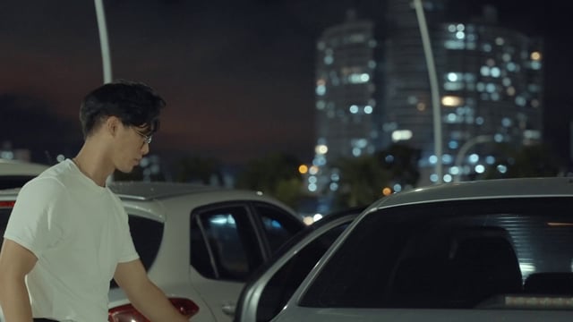 Asian man getting a jacket out of his car
