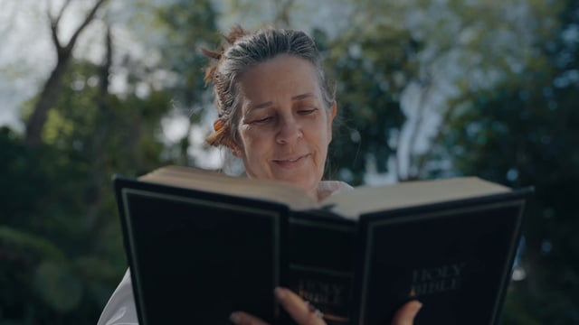 A smiling woman reads a Holy Bible