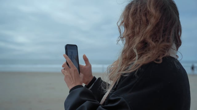 Una niña está filmando un video en la playa.