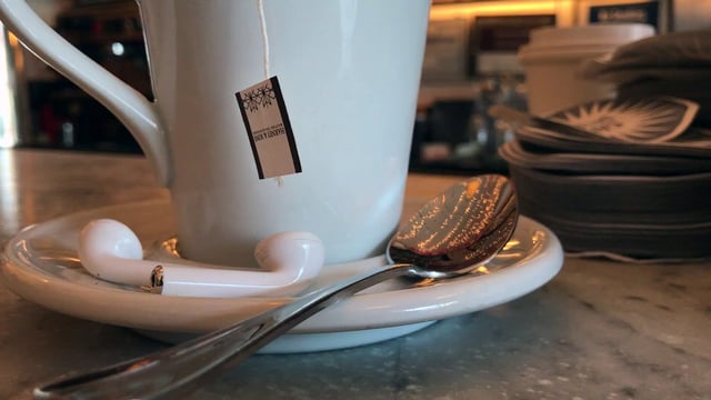A cup of tea with AirPods next to it