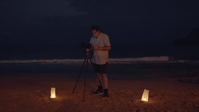 A man filming on the beach with his camera