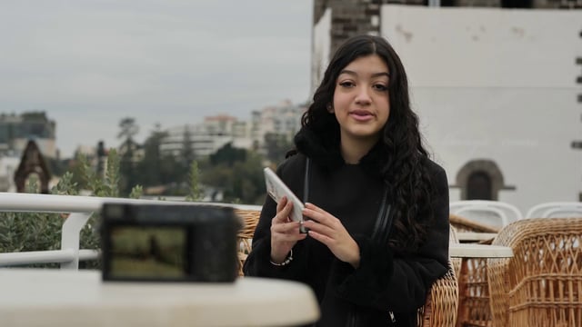 Una chica grabando un vlog en la terraza de un café