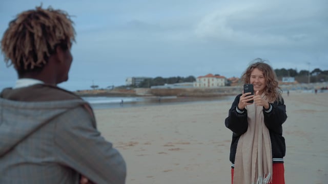 Una niña fotografía a su amigo en la playa.