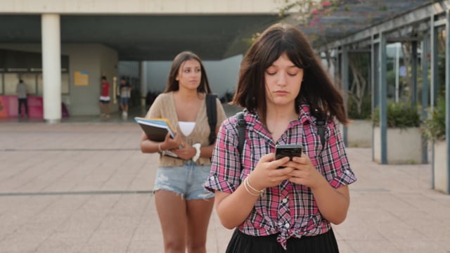 Estudiantes caminando y enviando mensajes de texto en el campus.
