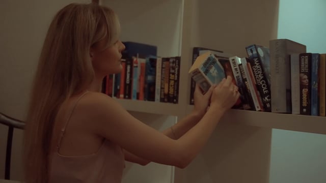 Woman taking a book from a bookshelf