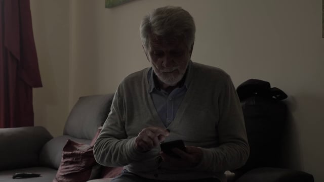 Un anciano muestra a alguien un retrato en un teléfono inteligente