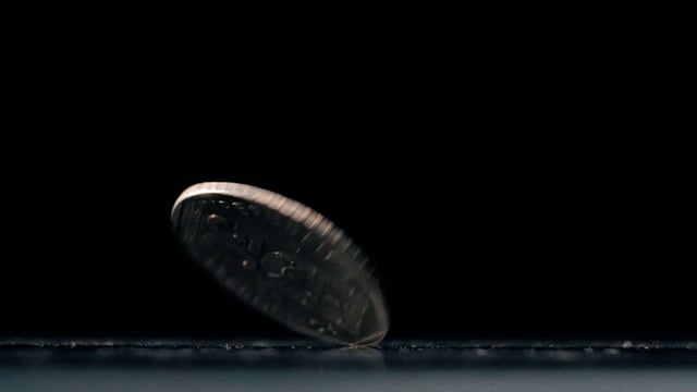 An old coin is spinning on a black background
