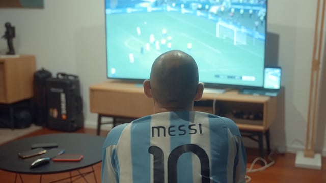 Un chico está viendo un partido de fútbol.