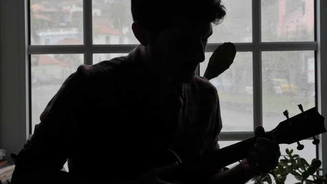 Silhouette of a man as he plays the ukulele