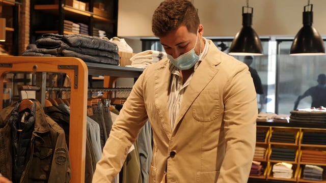 Un consultor ayuda a un cliente a probarse una chaqueta