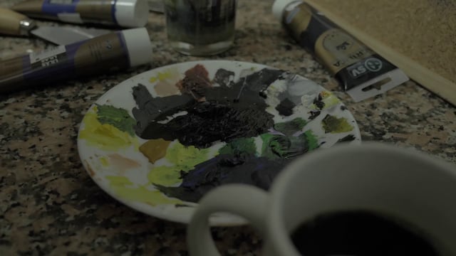 Un artista enjuaga un pincel en agua y toma una nueva pintura negra