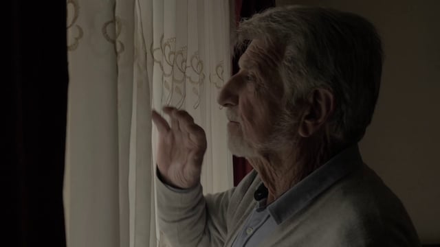Un anciano mira por la ventana