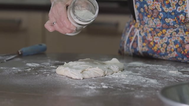 Woman sprinkling flour on dough