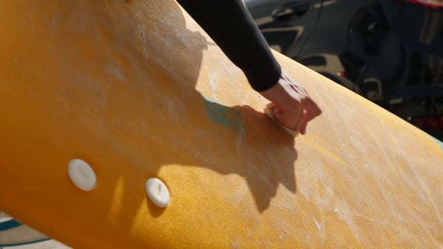 Rubbing wax on a surfboard